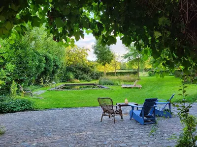 a patio with chairs and a table in a park at Charming and cosy ART DECO house in old historic farm with private natural pool and gardens with hiking and cycling trails nearby in Sint-Truiden