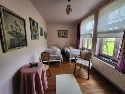 a room with two beds and a table and chairs at Charming and cosy ART DECO house in old historic farm with private natural pool and gardens with hiking and cycling trails nearby in Sint-Truiden