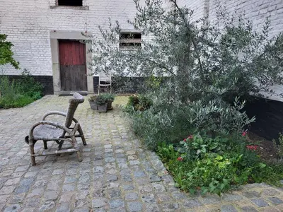 a bench sitting in front of a building at Charming and cosy ART DECO house in old historic farm with private natural pool and gardens with hiking and cycling trails nearby in Sint-Truiden