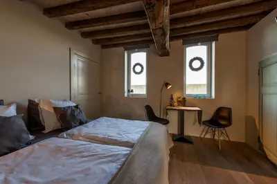 a bedroom with a bed and a desk and two windows at Holiday Home Janssen & Janssen in Maasmechelen