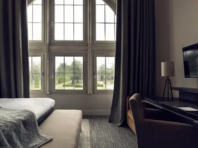 a bedroom with windows and a bed and a couch at Terhills Hotel in Maasmechelen