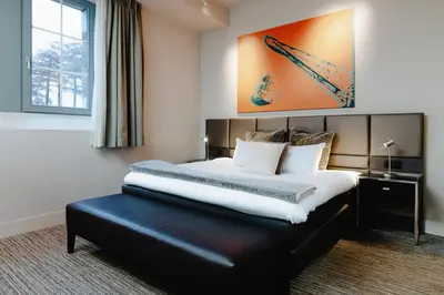 a bedroom with a large bed with a black leather seat at Terhills Hotel in Maasmechelen