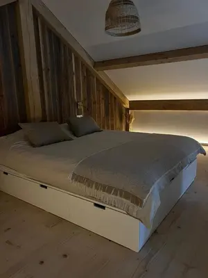 a large bed in a bedroom with wooden walls at Chalet Hoge Kempen in Zutendaal