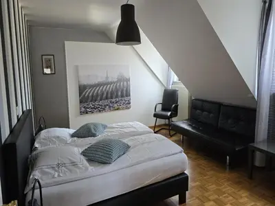 a bedroom with a bed and a black chair at Charming Group Stay in Borgloon in Borgloon