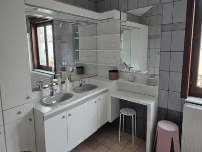 a bathroom with two sinks and a mirror and a stool at Charming Group Stay in Borgloon in Borgloon