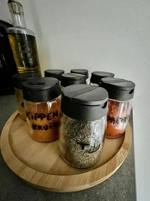 a group of four jars of spices on a wooden plate at Maison Isa in Lommel