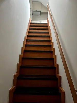 a stairway with brown wooden stairs and a white wall at Maison Isa in Lommel