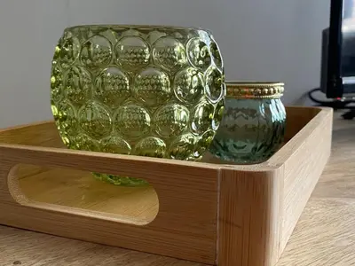 a green glass vase and a jar on a wooden shelf at 