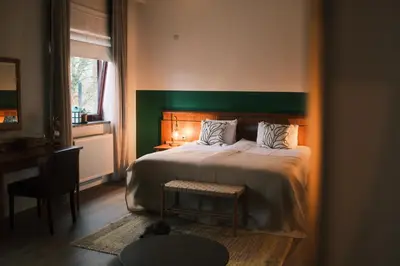 a bedroom with a large bed with a green headboard at Guesthouse De Wissen in Dilsen-Stokkem