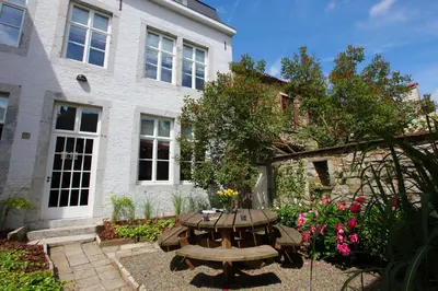 a picnic table in a garden in front of a building at Le Dragon Limbourg - Luxurious & Cozy Holiday Home in Limbourg