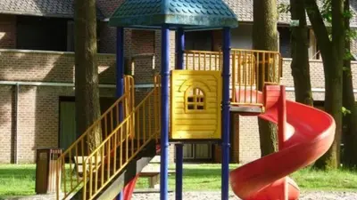 a playground with a slide in front of a building at Bos-Chalet bij Wijers Wandelroutes, Rust & Gezinsplezier Fijnspar 6 Hengelhoef in Houthalen-Helchteren