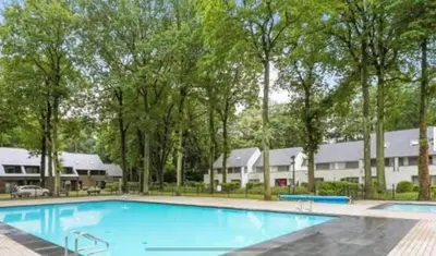 a large blue swimming pool with trees in the background at Bos-Chalet bij Wijers Wandelroutes, Rust & Gezinsplezier Fijnspar 6 Hengelhoef in Houthalen-Helchteren