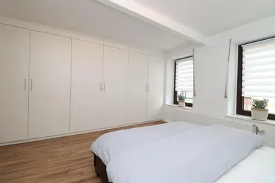 a white bedroom with white cabinets and a bed at Louisappart - Eupen Zentrum in Eupen