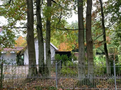a fence in front of a white house with trees at Bokrijklodge in Hasselt