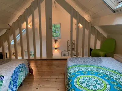 a bedroom with two beds and a green chair at Bokrijklodge in Hasselt