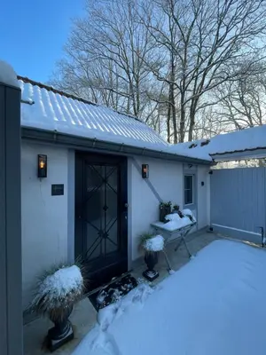 a white house with a black door in the snow at Bokrijklodge in Hasselt