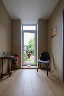 an empty room with a window and a chair at Gîte La Vieille Ferme Chaudfontaine et son jacuzzi in Chaudfontaine