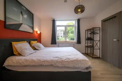 a bedroom with a large bed with an orange wall at Gîte La Vieille Ferme Chaudfontaine et son jacuzzi in Chaudfontaine
