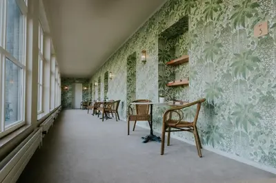 a row of chairs and tables in a room with green wallpaper at Château de Looz in Borgloon