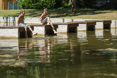 two boys sitting on a ledge in the water at Jocomo Parc in Lanaken