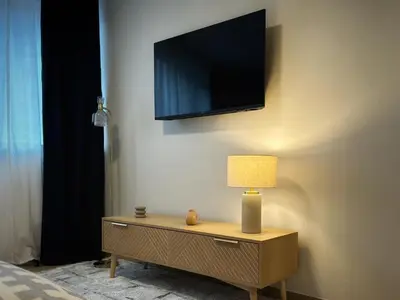 a tv on a wall with a table with a lamp at Suite luxueuse aux Guillemins in Liège
