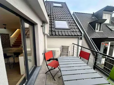 a balcony with red chairs and a table on a building at Le contemporain - Plein centre, place du Marché in Liège