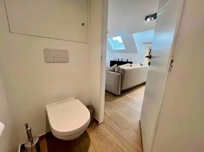 a white bathroom with a toilet and a couch at Le contemporain - Plein centre, place du Marché in Liège