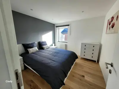 a bedroom with a bed with blue sheets and a window at charmante maison 2 chambres, entièrement rénovée in Jeuk