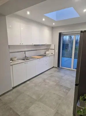 a kitchen with white cabinets and a large window at charmante maison 2 chambres, entièrement rénovée in Jeuk