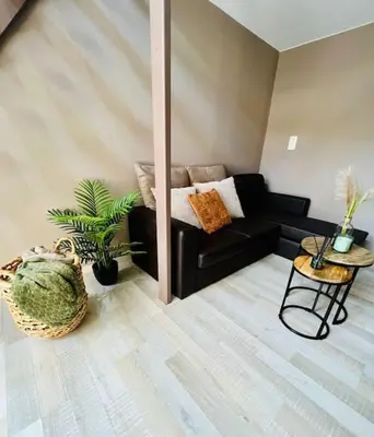 a living room with a black couch and a table at Appartement tropical in Liège