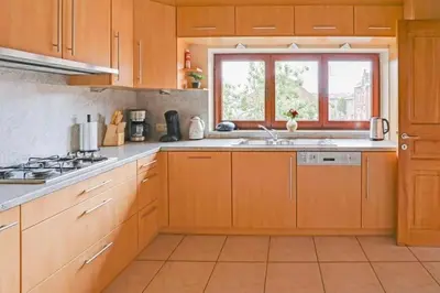 a kitchen with wooden cabinets and a sink and a window at Bij Suus onder de wol in Borgloon