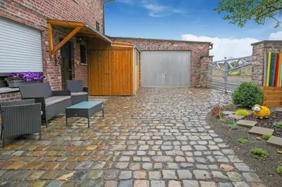 a patio with a brick building with a garage at Bij Suus onder de wol in Borgloon
