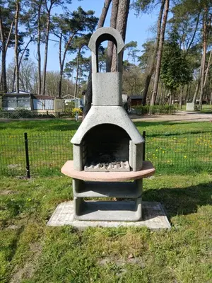 a stone oven sitting in the grass in a park at Vakantie-Chalet Camping GOOLDERHEIDE met seizoensgebonden zwembad in Bocholt