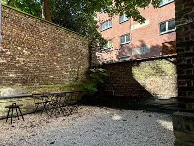 a brick wall with two tables in front of a building at Havre des Anges - Pont de Fragnée, Guillemins in Liège