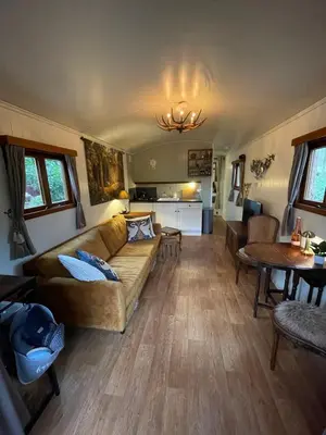 a living room with a couch and a table at Pipowagen de Zwaan in Hoge Kempen nabij Maastricht in Lanaken