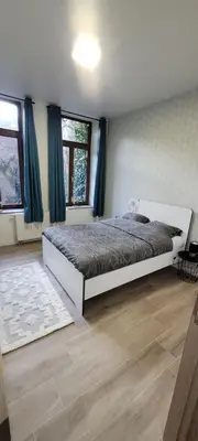 a bedroom with a bed in a room with windows at Au pied du théâtre in Verviers