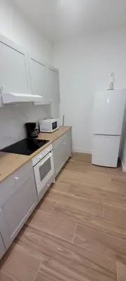 a kitchen with white cabinets and a wooden floor at Au pied du théâtre in Verviers