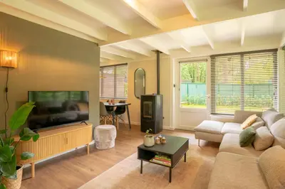 a living room with a couch and a flat screen tv at Boshuisje Rekem - Silas in Lanaken