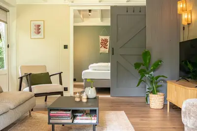 a living room with a sliding barn door and a bedroom at Boshuisje Rekem - Silas in Lanaken