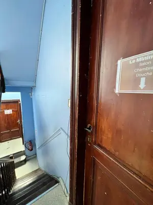 a door with a sign on it next to a stairs at Le Minimum in Liège