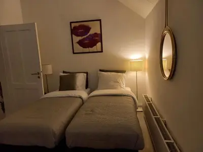 two beds in a small room with a mirror at Casa Barata in Riemst