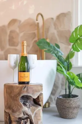 a bottle of wine on a wooden stump with a plant at Ontspan huisje: wellness in de natuur in Lanaken