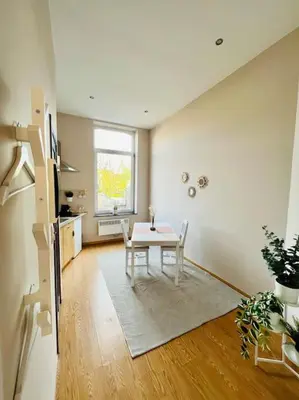 a dining room with a table and a kitchen at Charmant petit appartement. in Liège