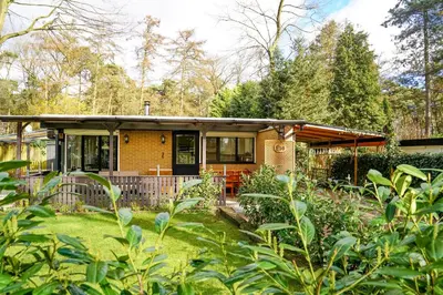 a brick house with a porch in a garden at Boshuisje De Eekhoorn in Lanaken