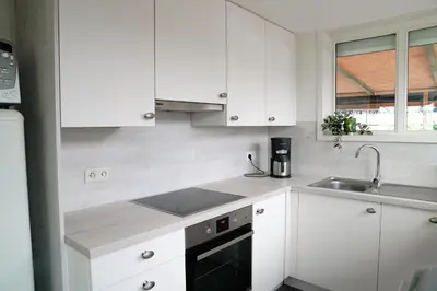 a white kitchen with white cabinets and a sink at Boshuisje De Eekhoorn in Lanaken
