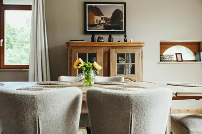 a dining room with a table with chairs and a vase of flowers at Au pied du Pré by WelcHome in Verviers