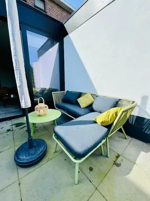 a patio with a couch and a table and a lamp at Stylish Home near Maastricht Alicias house in Lanaken