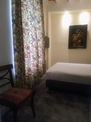 a bedroom with a bed and a chair and a curtain at KolMojen in Sint-Truiden