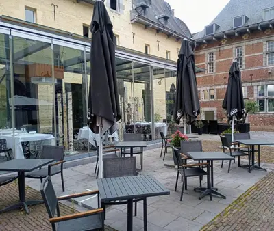 an outdoor patio with tables and umbrellas at KolMojen in Sint-Truiden