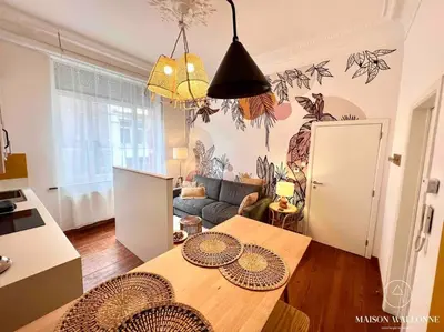 a living room with a table and a couch at Le cocon rose - Chic, proche Jardin botanique in Liège